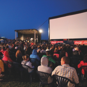 Viele Menschen sitzen vor der noch weißen Leinwand beim Open Air Kino am Meer in Norddeich